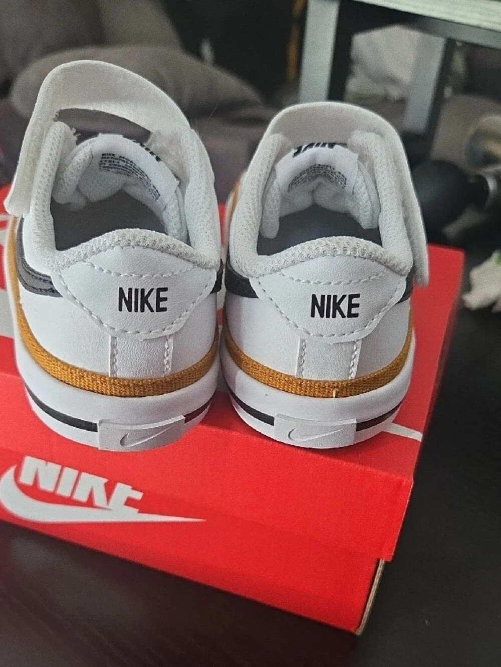 Nike Kids White Sneakers with Black Swoosh and Gold Accent